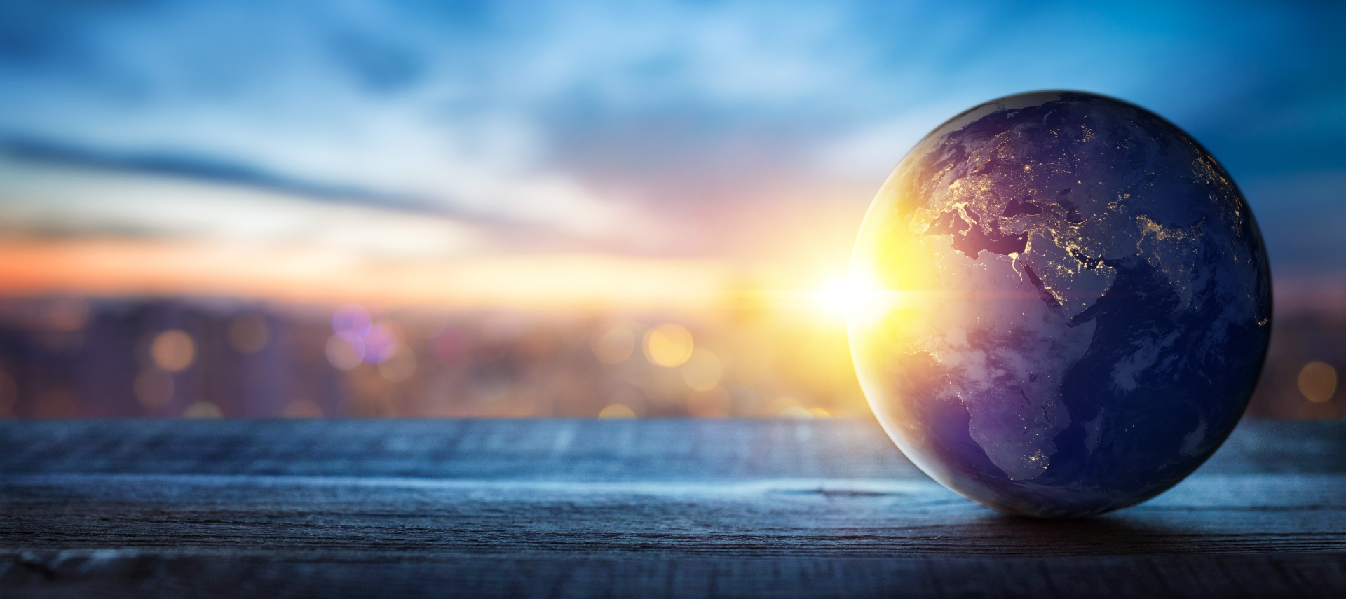 Globe with sunrise, symbolizing global connectivity and new beginnings. Blurred cityscape background with colorful lights.