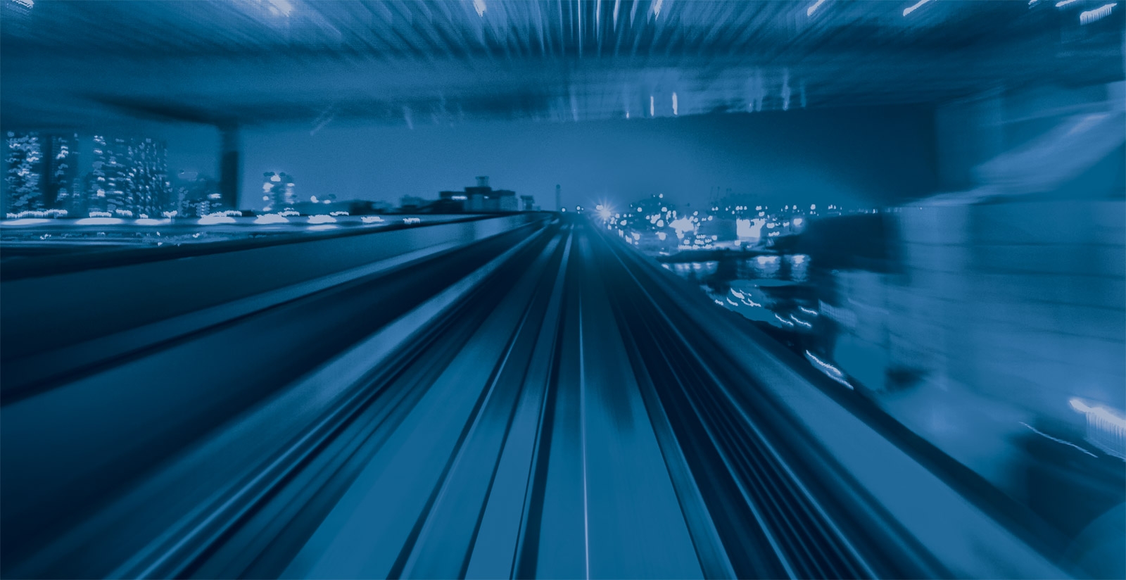 High-speed train moving through a city at night, with blurred motion and city lights creating a futuristic effect.